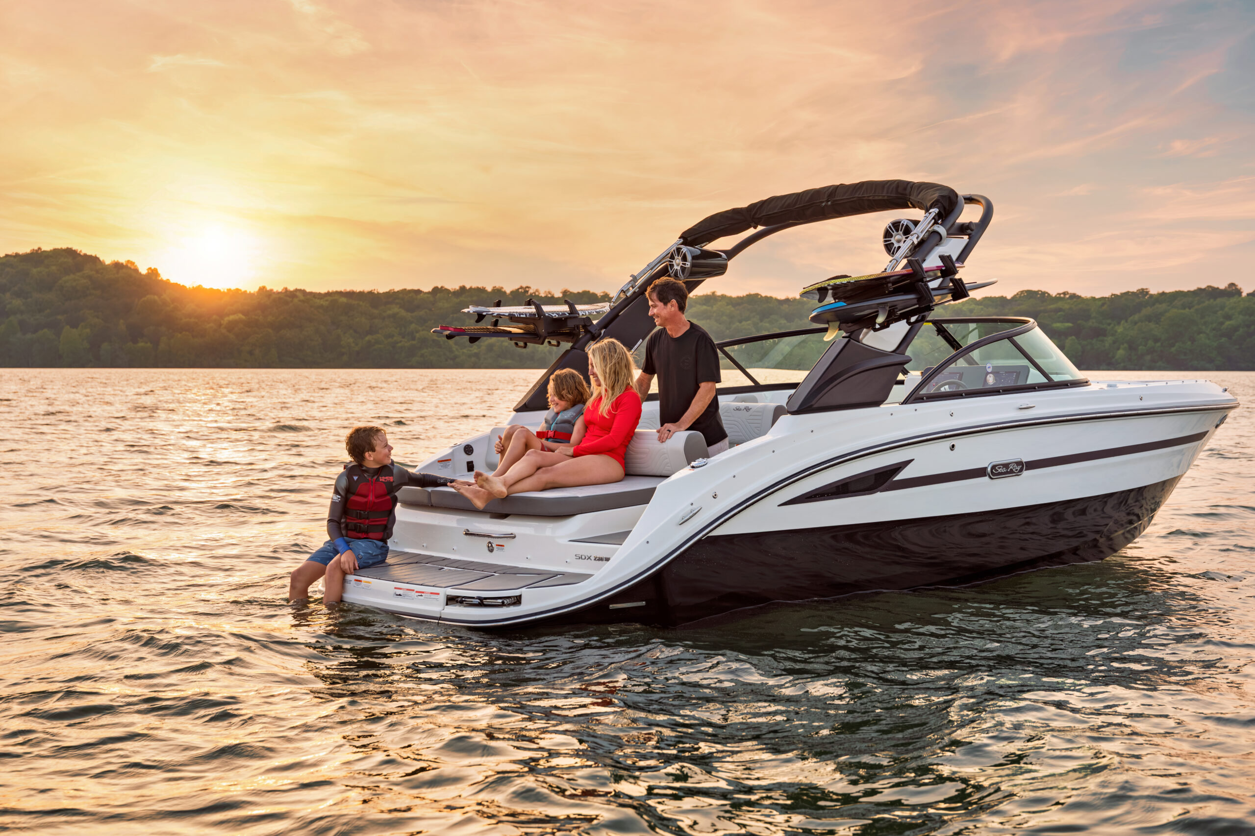 Family aboard an SDX 230 Surf at sunset